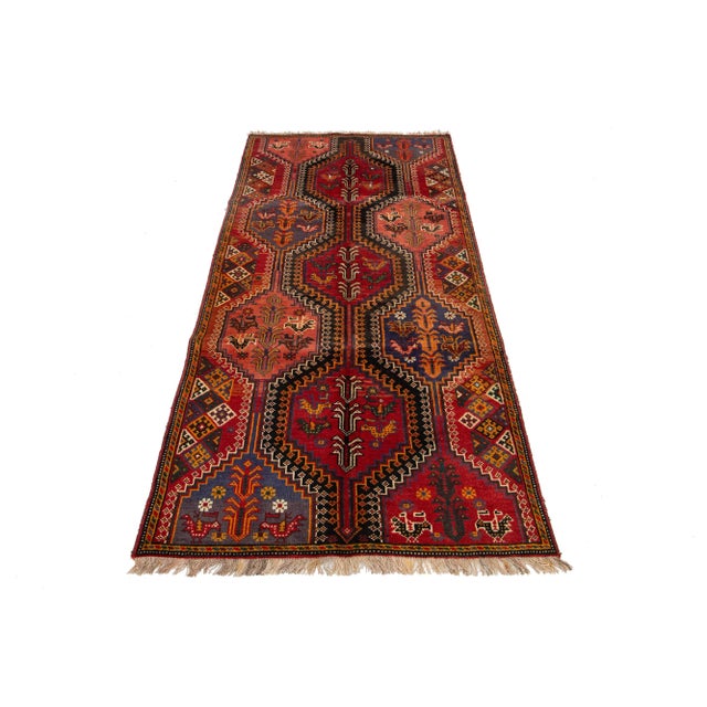 This exquisite vintage Persian Shiraz rug is meticulously-knotted from high-quality wool. It features a rich red field...