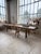 An antique, large-format table with a workbench-style top and a brutalist or folk art base. the top, likely from a very...