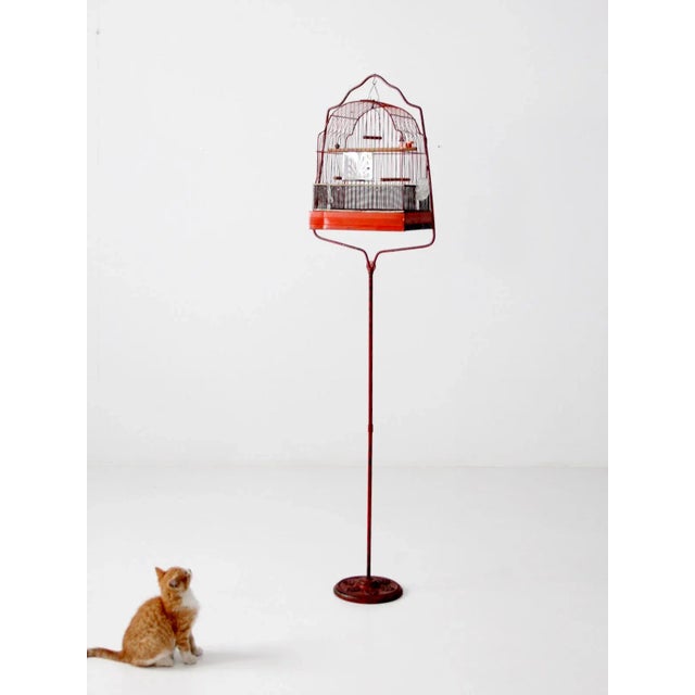 Antique birdcage with iron stand featuring a red metal Crown cage and charming original details. Two glass feeders, three...