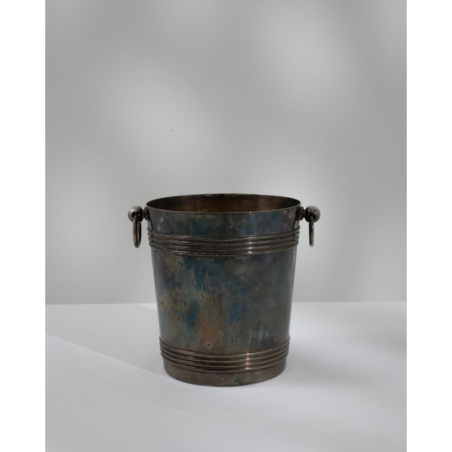 A 20th century French champagne bucket crafted in metal with a silver-plated finish, featuring a cylindrical form with...