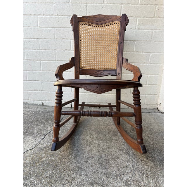 Vintage Victorian rocking chair featuring a dark wood frame, a woven cane back, and a cane seat in excellent condition....