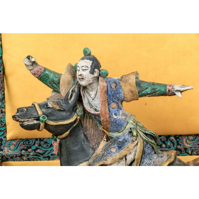 An antique polychrome glazed ceramic roof tile sculpture depicting a horseman in dynamic mid-gallop pose, with arms flung...