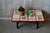 This coffee table is a production from the 60s. Its top, bordered by a wooden edge, is made of ceramic tiles: floral...