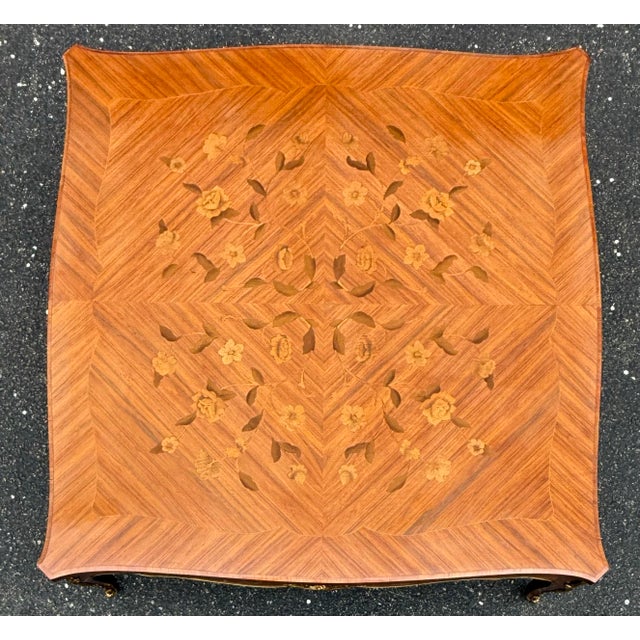 Spectacular French Provincial coffee table features intricate marquetry details with a central floral motif surrounded by...