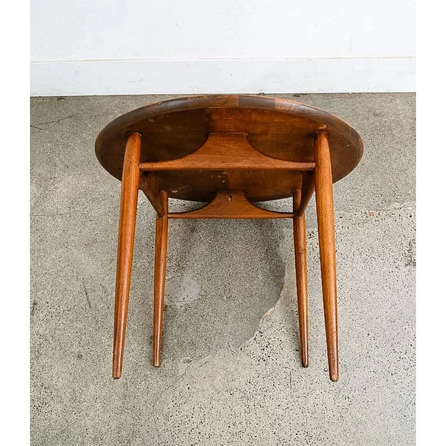 Iconic round end table in walnut by Heritage Henredon. This item has been recently refinished. The table is marked beneath.