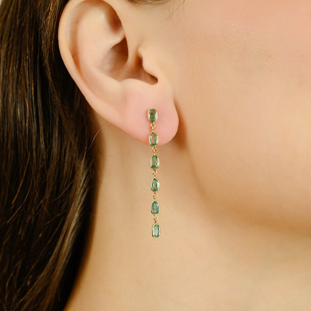 Elevate your look with these stunning 14K gold emerald drop earrings. Each earring features a delicate line of natural...