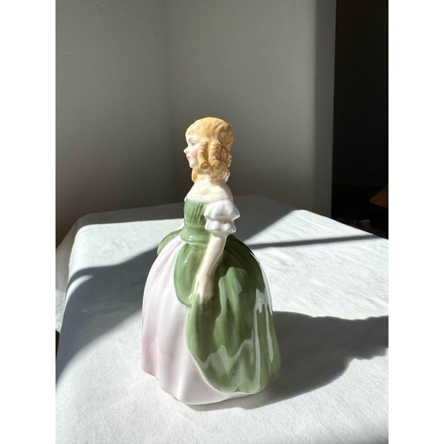 The Royal Doulton Figurine "Penny" HN 2338 is a delightful embodiment of youthful charm and classic English elegance....