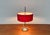 Mid Century table lamp with red shade. The simple drum shade is covered in red and has a roof made of white parchment. It...