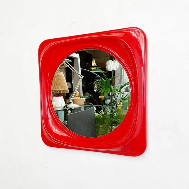 Red plastic mirror, 1980s. Mirror with square frame and rounded corners in red plastic and round internal mirror. Good...