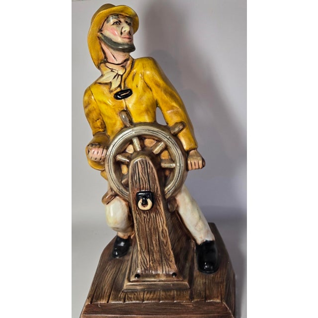 A folksy, handpainted captain bedecked in wet weather wear struggles against the ships wheel in this piece. Please check...