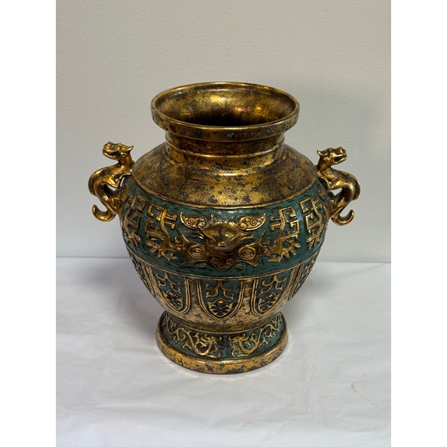 Striking and sculptural, this Chinese-style decorative vase is crafted from cast bronze-toned metal with a richly mottled...