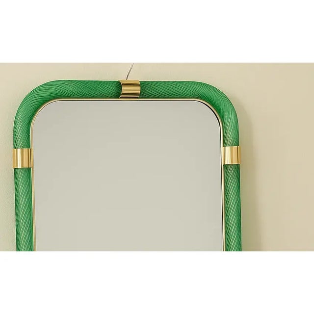 Scenographic luxury wall mirror in brass elements in green color working in "torciglione". a traditional tecnique of...