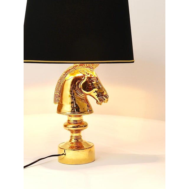 A gold-plated sculptural Hollywood Regency style table lamp from the 1970s in the shape of a horse chess piece. Made of...