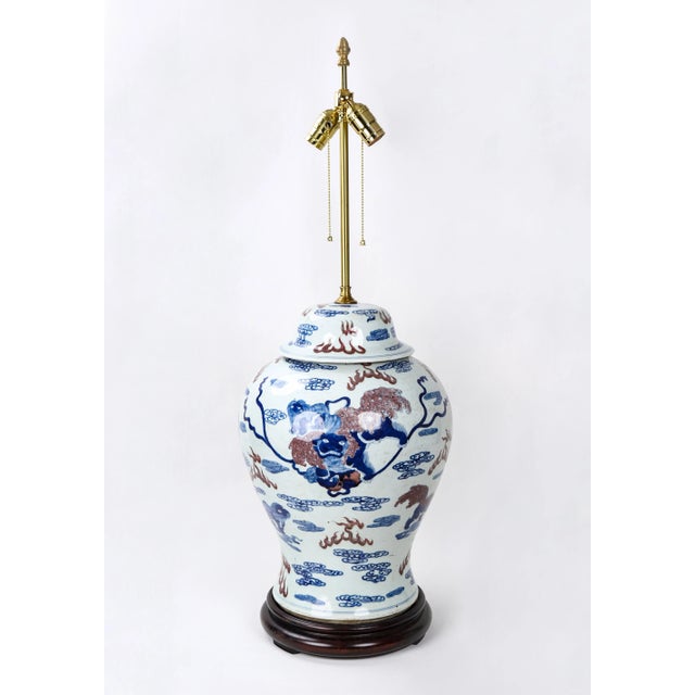 This is a table lamp made of a 19th century jar. The jar is hand-painted with patterns of red clouds and lions in blue and...