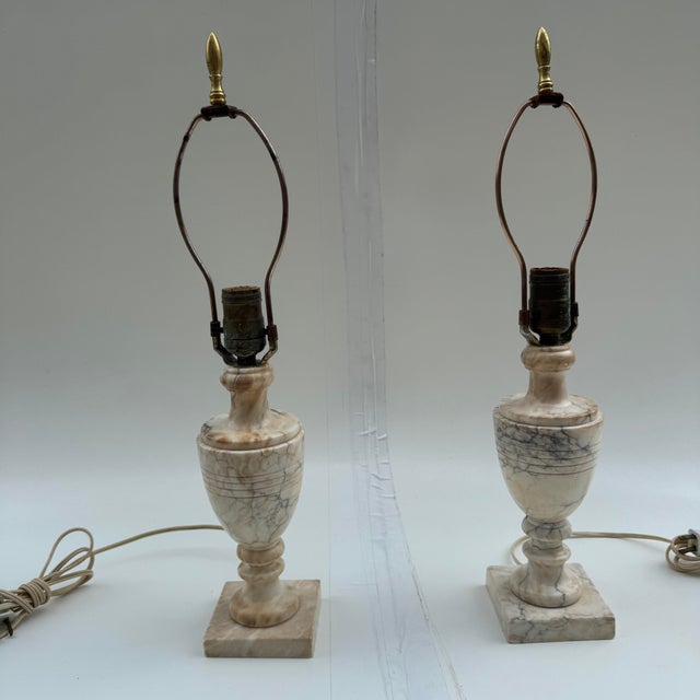 Pair of Italian alabaster table lamps with harps and brass bullet shaped finials. Marked Italy on the base. When I...