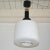 Classic Stilnovo 1960s pendant in milk glass edged with a metal rim hanging from a black metal and brass lamp holder. This...