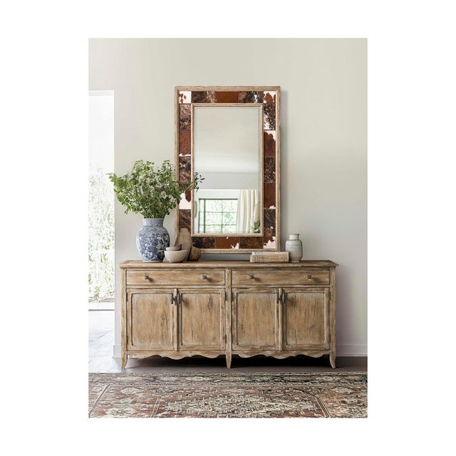 The wall mirror adds a bold, handcrafted touch to any room with its mix of natural cowhide and weathered wood. The...