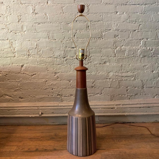 Large, art pottery table lamp by Gordon Martz for Marshall Studios features a muted gray, striped base with teak neck and...