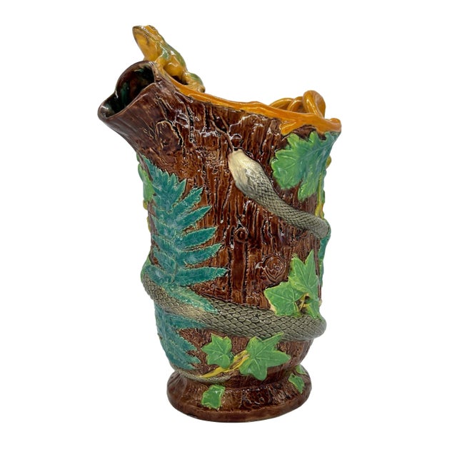 A Samuel Alcock Majolica Pitcher, the body molded as a tree trunk with ferns, oak leaves, acorns, and ivy, entwined by a...