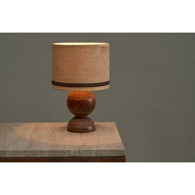 A lovely table lamp with a base in carved wood with a shade in woven jute. Probably french, 1960s. The lamp features a...