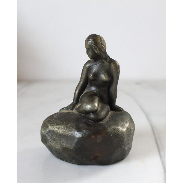 Vintage cast metal mermaid figure sitting on rock. Made in Denmark. Some light age wear.
