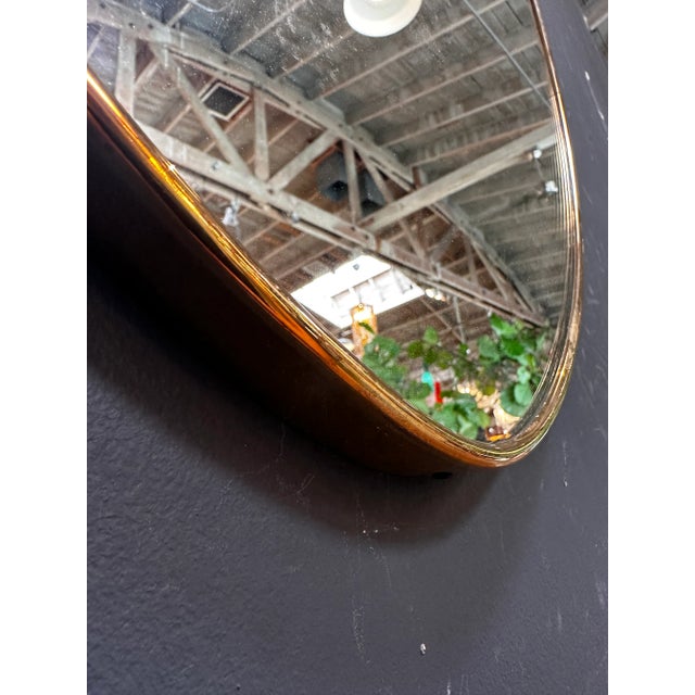 The Vintage Italian 1960s Curvilinear Brass Wall Mirror is a stylish and unique piece showcasing elegant curves in brass.