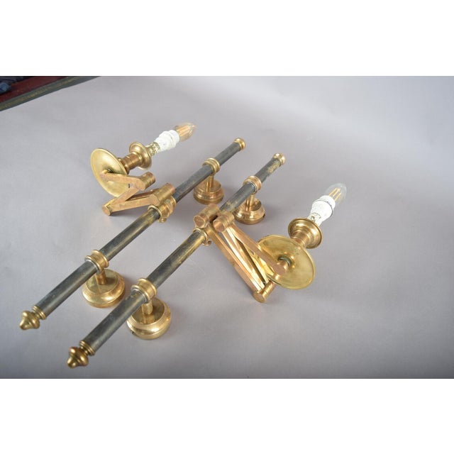 A rare and elegant pair of brass swing-arm wall lamps attributed to maison jansen, the renowned parisian decorating house...