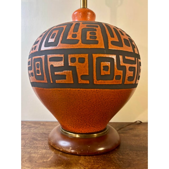 A striking large-scale Mid-Century Modern ceramic table lamp featuring a richly saturated orange glaze over dark clay. The...