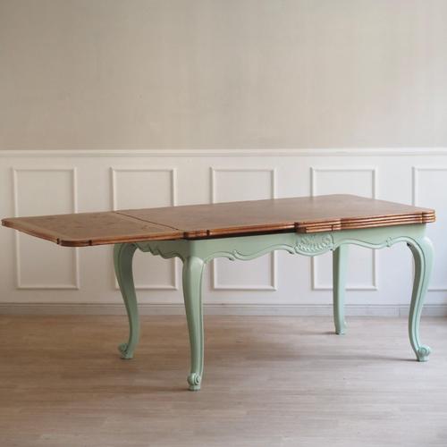 A beautiful and unique french country-style dining table with mint green legs and an artfully crafted natural wood top....