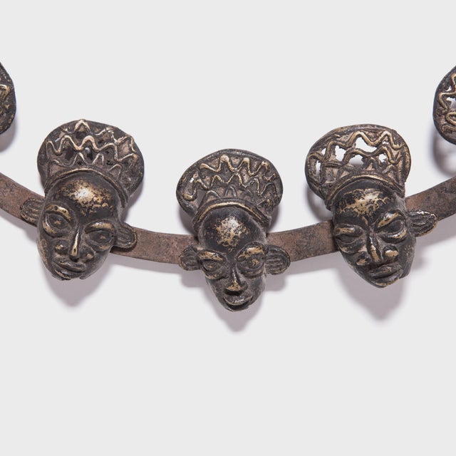 Composed of fifteen miniature heads welded onto a circular form, this intricate necklace is styled after the prestige...