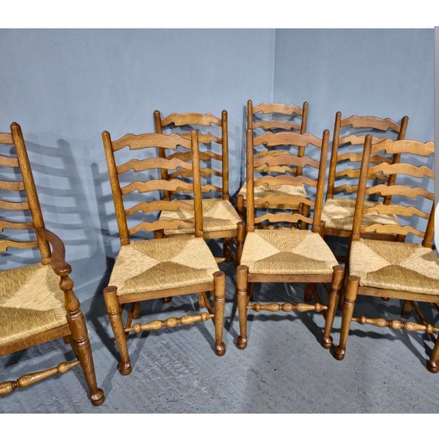 A super set of eight golden oak ladder backed dining chairs with rush seats, includes two carvers, in excellent overall...