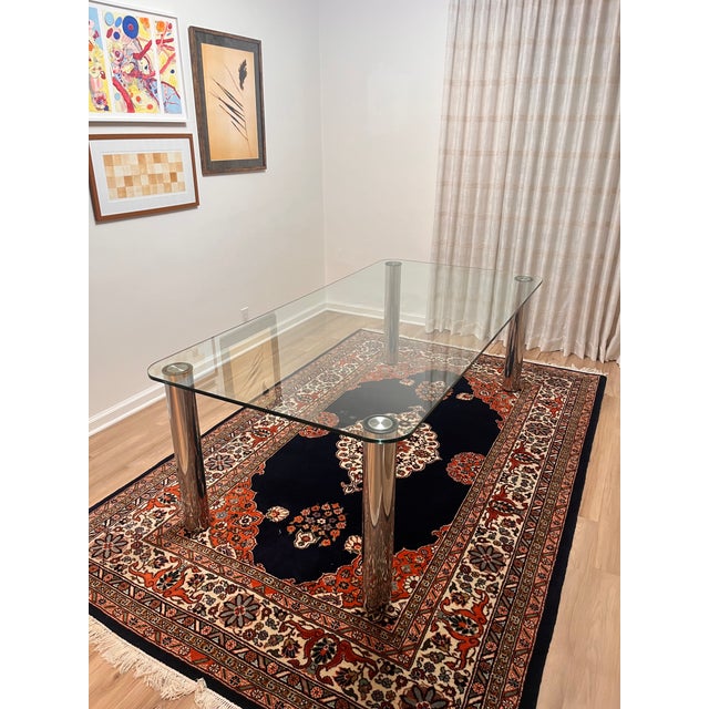 A sleek, postmodern glass dining table with four polished chrome-plated legs — a striking example of 1980s/90s design,...