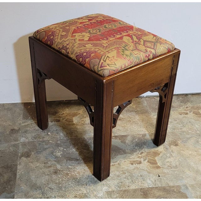 A handsome early 20th century mahogany stool in the Chippendale style, featuring rich, vibrant upholstery reminiscent of...
