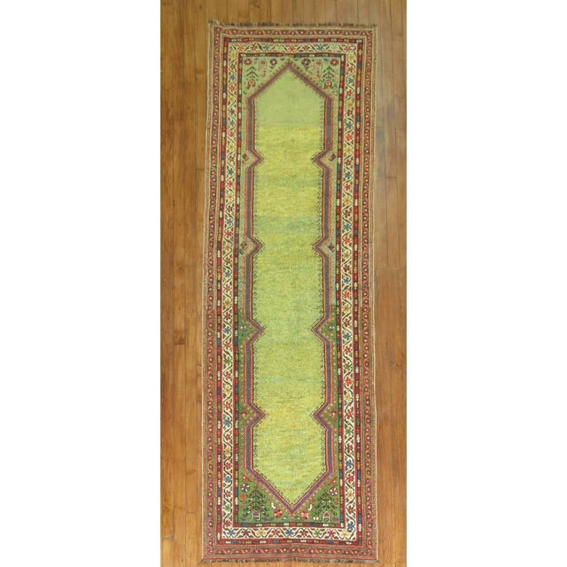 A fascinating early 20th century Persian runner with an open lime green field.