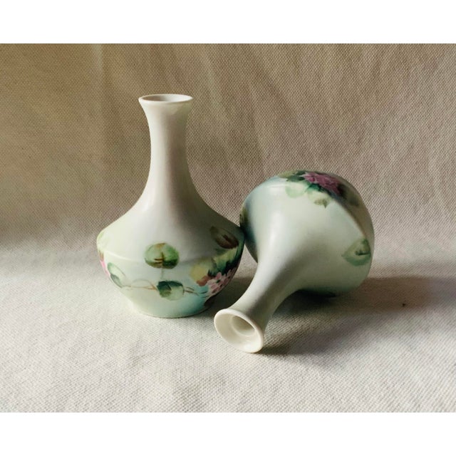 ….a perfectly matched pair of petite hand-painted French porcelain bud vases, brimming with the charm and artistry of the...