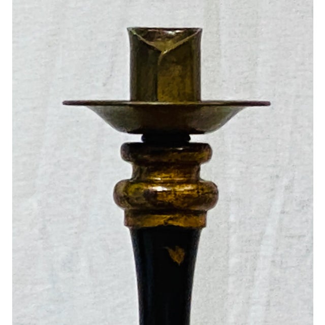 A striking floor candle stand by Maitland Smith, finished in black with gilt accents and intentional distressing to evoke...