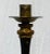 A striking floor candle stand by Maitland Smith, finished in black with gilt accents and intentional distressing to evoke...