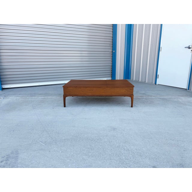 This mid-century modern walnut coffee table by Lane combines sleek, sculptural design with clever functionality. Crafted...