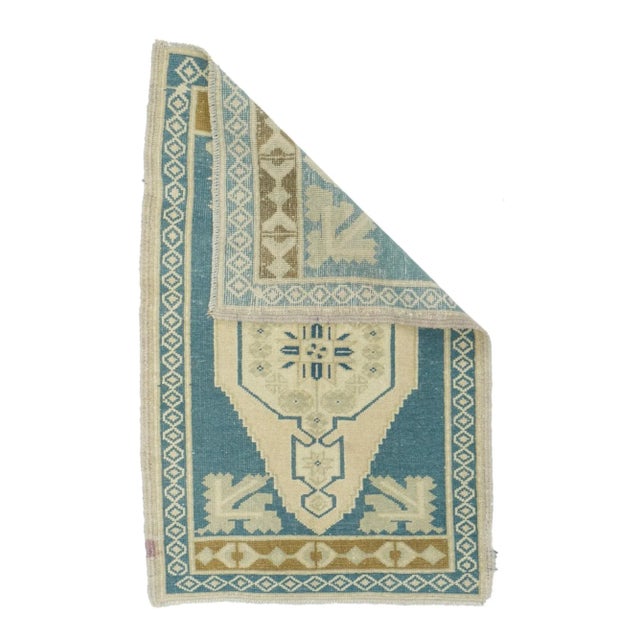 This mat (yastik, cushion cover) shows a slate open field with palest green corner flower sprays, setting off a sandy-...