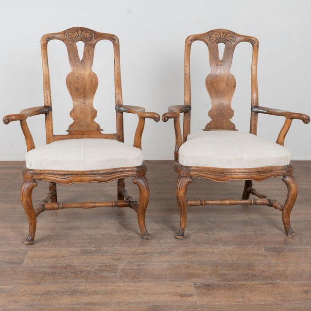 Pair of 18th-century Swedish baroque armchairs with a deep, rich brown patina. The sculpted arms and cabriole legs rest...