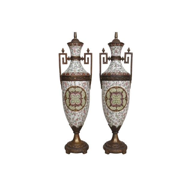 A pair of Renaissance style patinated bronze and porcelain urn table lamps. Each urn is hand painted with a pink floral...