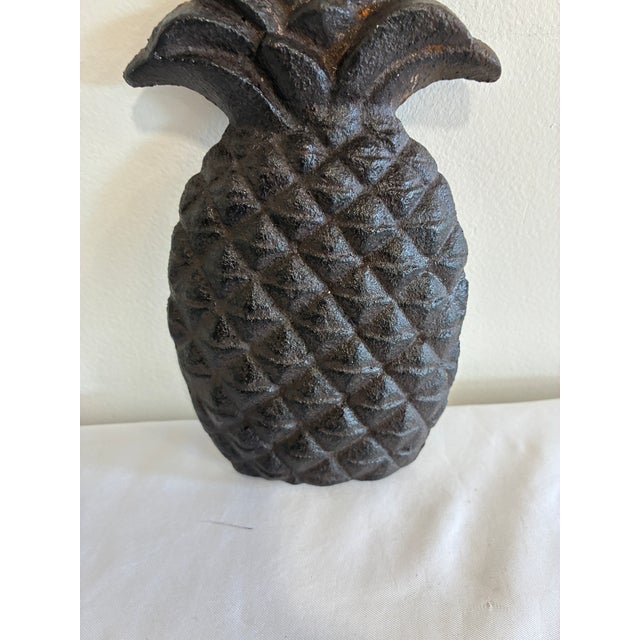 A charming cast iron pineapple with crisp, sculpted diamond detailing and an elegant fan of leaves. The deep charcoal-...