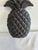A charming cast iron pineapple with crisp, sculpted diamond detailing and an elegant fan of leaves. The deep charcoal-...