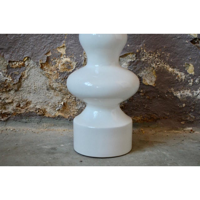 Large, made of white earthenware, and featuring lines reminiscent of a totem pole, this vase exudes vintage energy and...