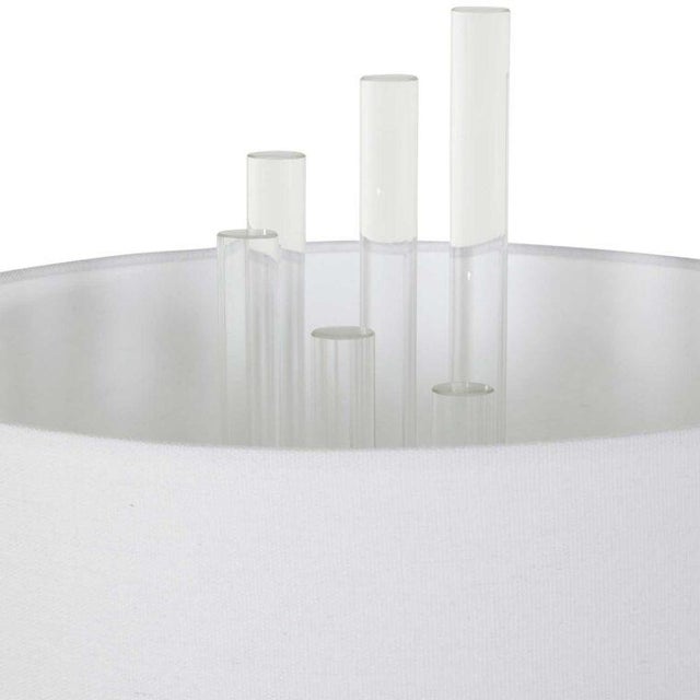 The Merna Table Lamp Clear crystal rods shoot skyward from the Merna table lamp’s iron base straight through the white...