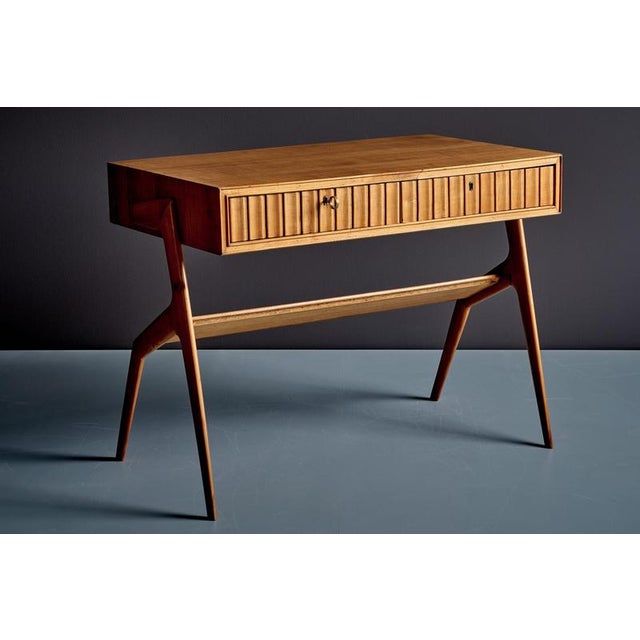 Italian cherry wood writing desk with a rectangular top that appears to float above the sculptural, tapered supports. The...