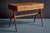 Italian cherry wood writing desk with a rectangular top that appears to float above the sculptural, tapered supports. The...