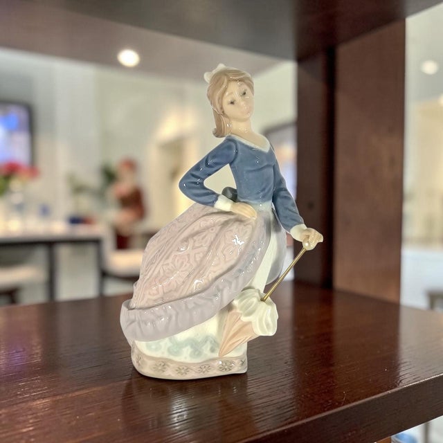 A Lladro Evita porcelain figurine, model #5212, from the Girls with Parasols collection. Introduced in 1984 and produced...