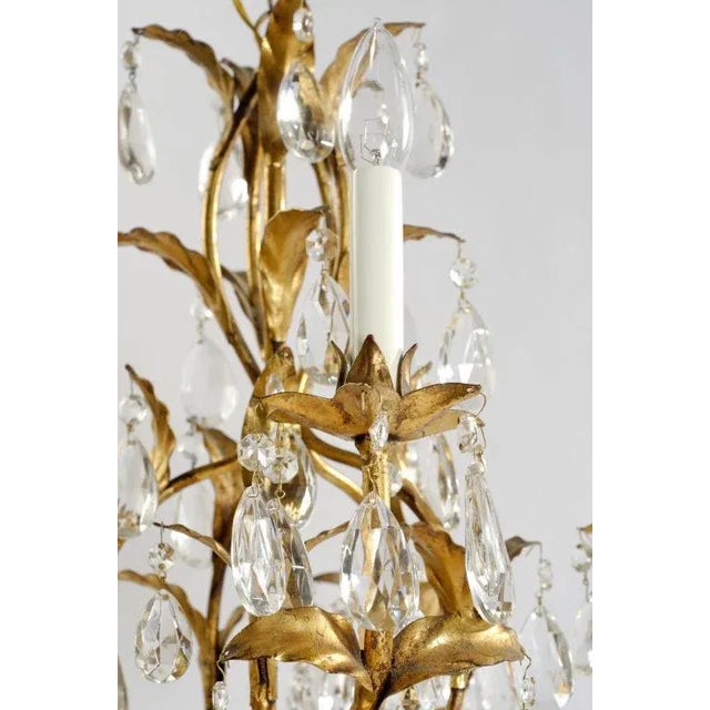 Gilded metal foliage supported by five arms with lights. Many crystal drops embellish the fixture.