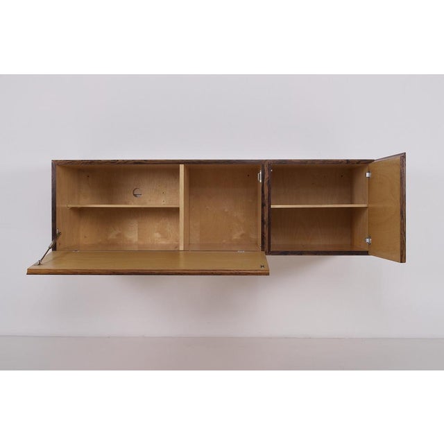 Modernist rosewood sideboard, wall-mounted, composed of three freestanding (but not interchangeable) cabinets. A 1960s...